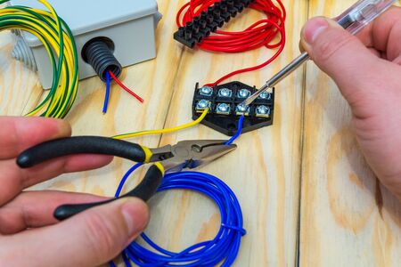 The master holds an electric tool and wires of different colors to connect