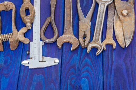 Many vintage craftsman tools stacked after work on blue wooden boards