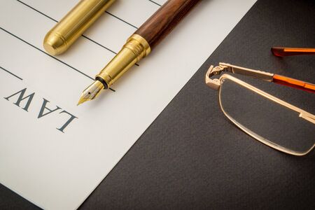 Office still life on a black table with pen on sheet and glasses preparing for recordings