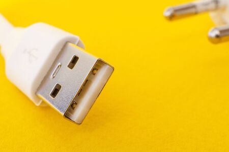 USB charger cable on yellow surface close up often used for charging a smartphone or tablet
