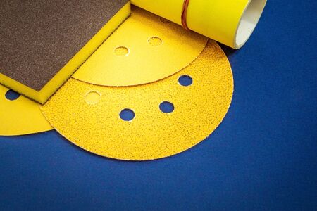 Big set of yellow abrasive tools and sandpaper on blue background wizard is used for grinding itemsの写真素材