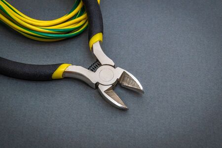 Pliers tool and wires for an electrician on a dark background are used by the master to repair electricityの写真素材
