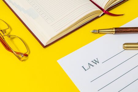 Office still life on yellow table with gilt pen, notebook and law preparing for notesの写真素材