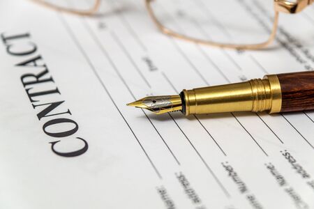 Stylish pen and glasses lie on the form of the contract before drawing up