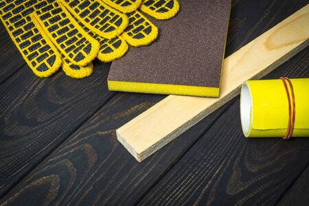 Work gloves and yellow sand paper for sanding wooden boards