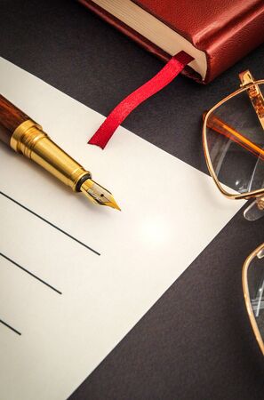 Office still life on a black table with pen on sheet and notepad preparing for recordingsの写真素材