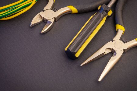 Electrician's tools and wire on a black background for repairing energized systems or communicationsの写真素材