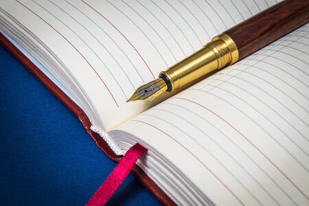 Gilt pen rests on open notebook for notes or writing textの写真素材