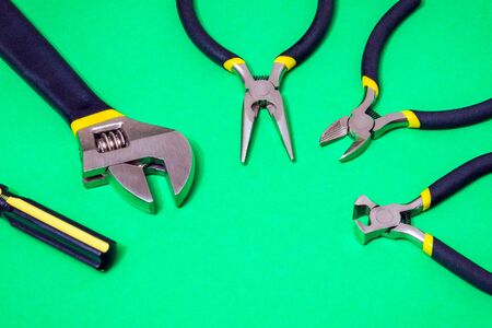 Large set of tools for master plumber or electrician on green isolated background