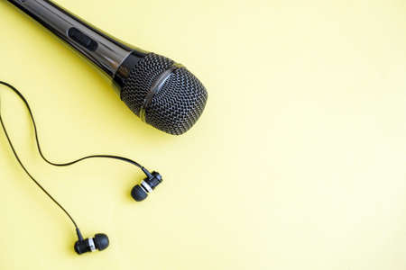 Gray microphone and headphones on yellow background with space for writingの写真素材