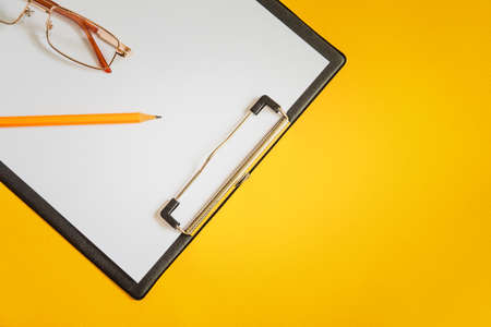 Blank sheet of paper and a pencil for writing on a yellow office Deskの写真素材
