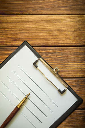 Paper sheet with empty to do list and a pen on vintage wooden table