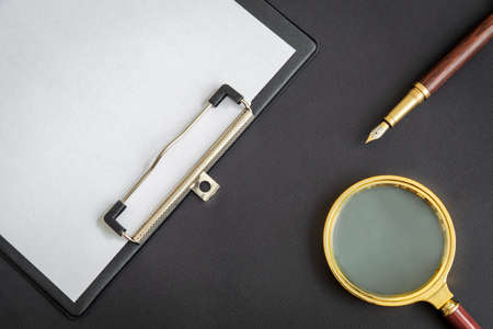 Magnifying glass and paper sheet with empty to do list and pen on black backgroundの写真素材