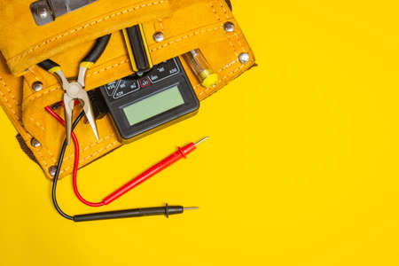 Set of tools in suede bag on yellow background prepared by the master electrician before repair or constructionの写真素材