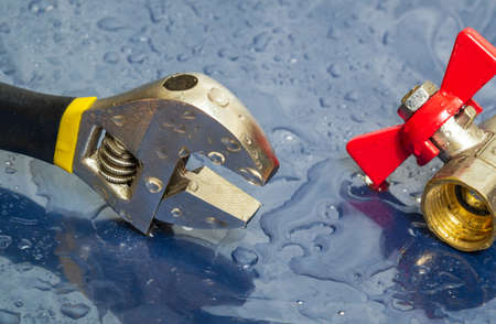 Plumbing faucet and wrench in water drops during equipment repair during an accident