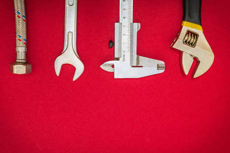 Set of tools and hose for plumbers on red background with space for advertisingの写真素材
