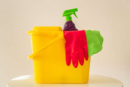 Cleaning products shampoo and red gloves in yellow bucket. Cleaner will create hygiene in the houseの写真素材