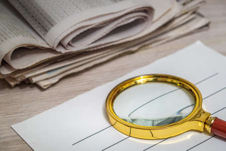 Magnifying glass for reading newspapers on a letterhead. Home environment during planning and analysisの写真素材