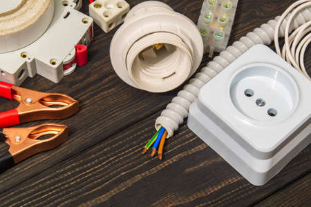 Kit spare parts for electrical repairs on black wooden boards. Workplace of master electrician.