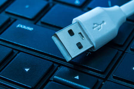 USB charger cable on computer keyboard closeup designed for connection or charger