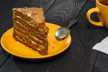 Piece of cake with cream layer in a plate and mug of tea on vintage table during dinnerの写真素材