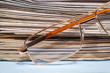 Reading glasses on the background of a stack of newspapersの写真素材