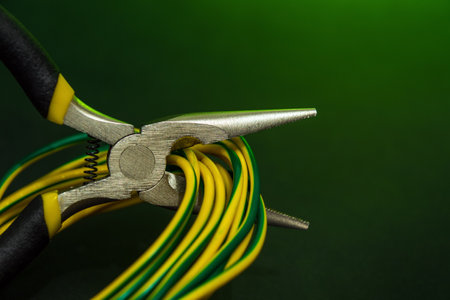 Round nose pliers with wires on a dark green background. Electricity repair idea