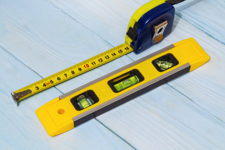 Building level and tape measure for leveling or measuring objects on blue boardsの写真素材