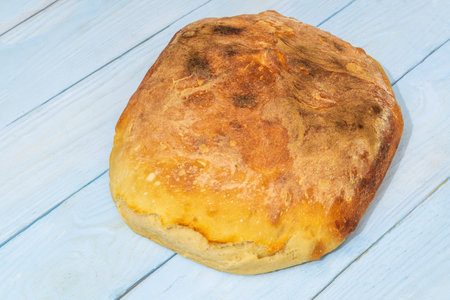 One baked loaf of Ukrainian national bread on a blue table