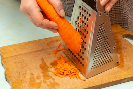 Women is hands brushing carrot with a grater. Healthy food, natural, organic vegetarian products. Cook at homeの写真素材
