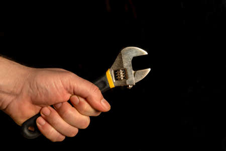Hand holding adjustable wrench isolated on black backgroundの写真素材