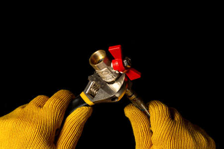 Plumber connects the hose to the ball valves using an adjustable wrench. Work combines elements of plumbing with the help of toolsの写真素材