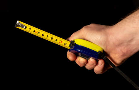 Man hand holds construction tape on black isolated background