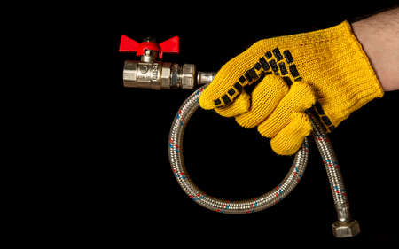Plumbing gloved hand holds a high pressure water hose with ball valves