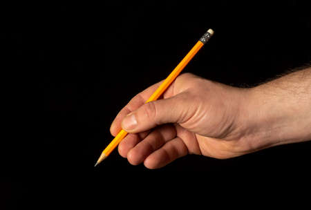 Closeup of male hand holding pencil on black isolated backgroundの写真素材