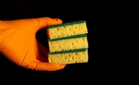 Hand in a glove holds three washcloths on black background close-up. The idea of cleaning premisesの写真素材