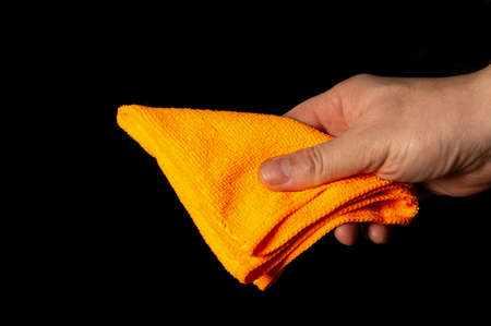 Hand man holds a bright duster on a black background. Home cleaning conceptの写真素材