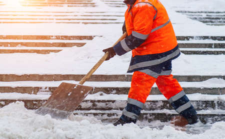 Snow removal. Worker clearing snow by shovel after snowfall. Outdoorsの写真素材