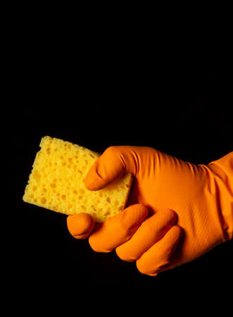 Gloved hand with washcloth on black background. The idea of cleaning premisesの写真素材