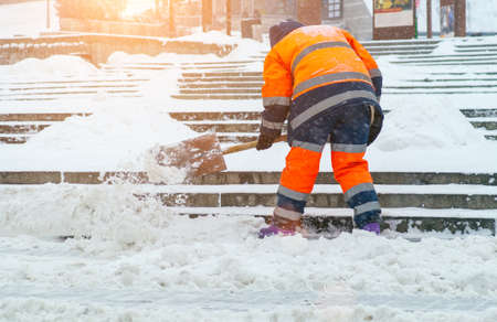 Snow removal. A worker cleans snow with a shovel after a snowfall at gatheringsの写真素材