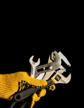 The hand in a work glove of the master holds a set of tools for repairing plumbingの写真素材