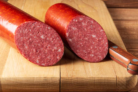 Sliced salami sausage and knife on cutting board. Food preparation idea before the holidayの写真素材