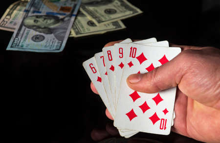 Poker cards with a straight flush combination. Close up of a gambler hand is holding playing cards...