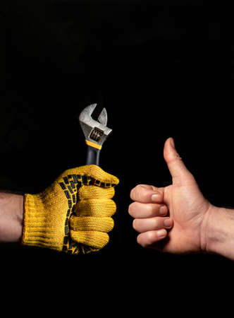 Close-up of people hands, one holds a wrench, and the other shows an ok sign. The concept of successful completion of the renovationの写真素材