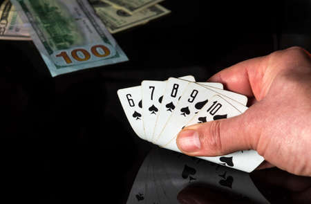 Poker cards with a straight flush combination. Close up of a gambler hand is holding playing cards...