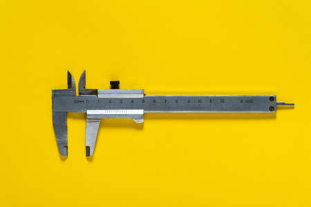 Old calipers on yellow background. Applied by craftsmen to repair plumbing or constructionの写真素材