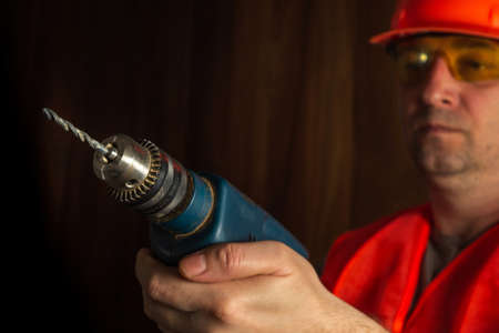 Woodworker holds an electric drill close-up during carpentry work. Working environment in a...
