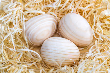 Three wooden eggs in a nest with wood shavings. Idea for celebrating Easter. Top viewの写真素材