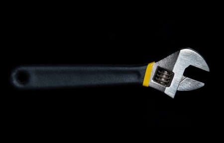 Adjustable wrench with rubber handle on black isolated background. It is used in the repair or...