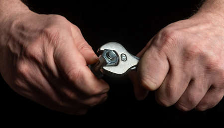 The master tightens the nut with a wrench on the bolt closeup. Idea for building or renovationの写真素材
